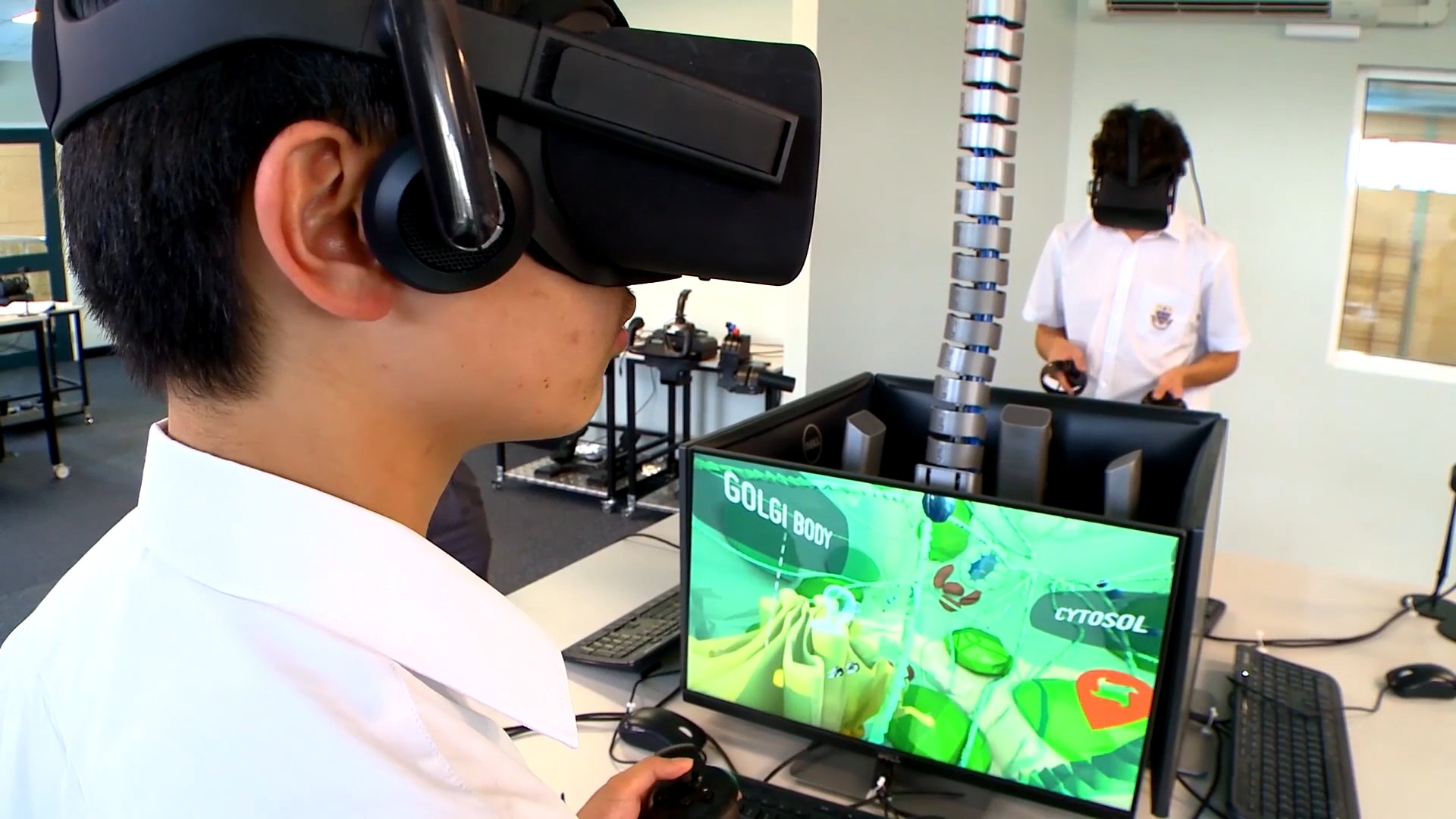 A student in a VR headset beside a monitor showing the Golgi body inside the virtual plant cell