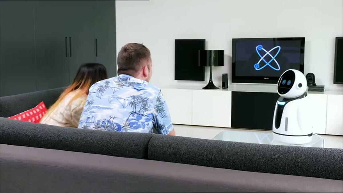 A couple on a sofa facing Jess, whose thinking animation is mirrored on the television behind her